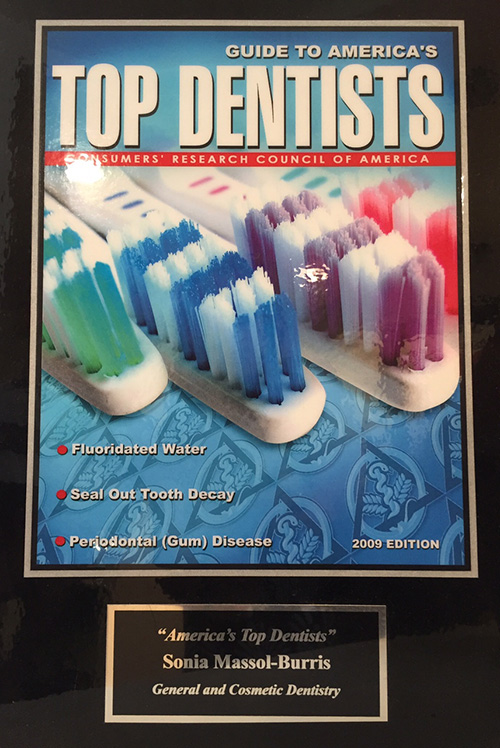 Cover of the guide to America's TOP DENTISTS, where you can see 4 white toothbrushes with different colors of bristles on a blue background, below a black plate with gold letters that say: America's Top Dentists, Sonia Massol-Burris, General and Cosmetic Dentistry