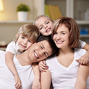 Family composed of father, mother, a girl and a boy wear white t-shirts and smile at the camera