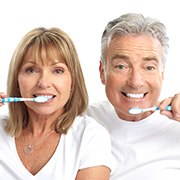 Adult woman and man hold toothbrushes close to their mouths, wear white t-shirts