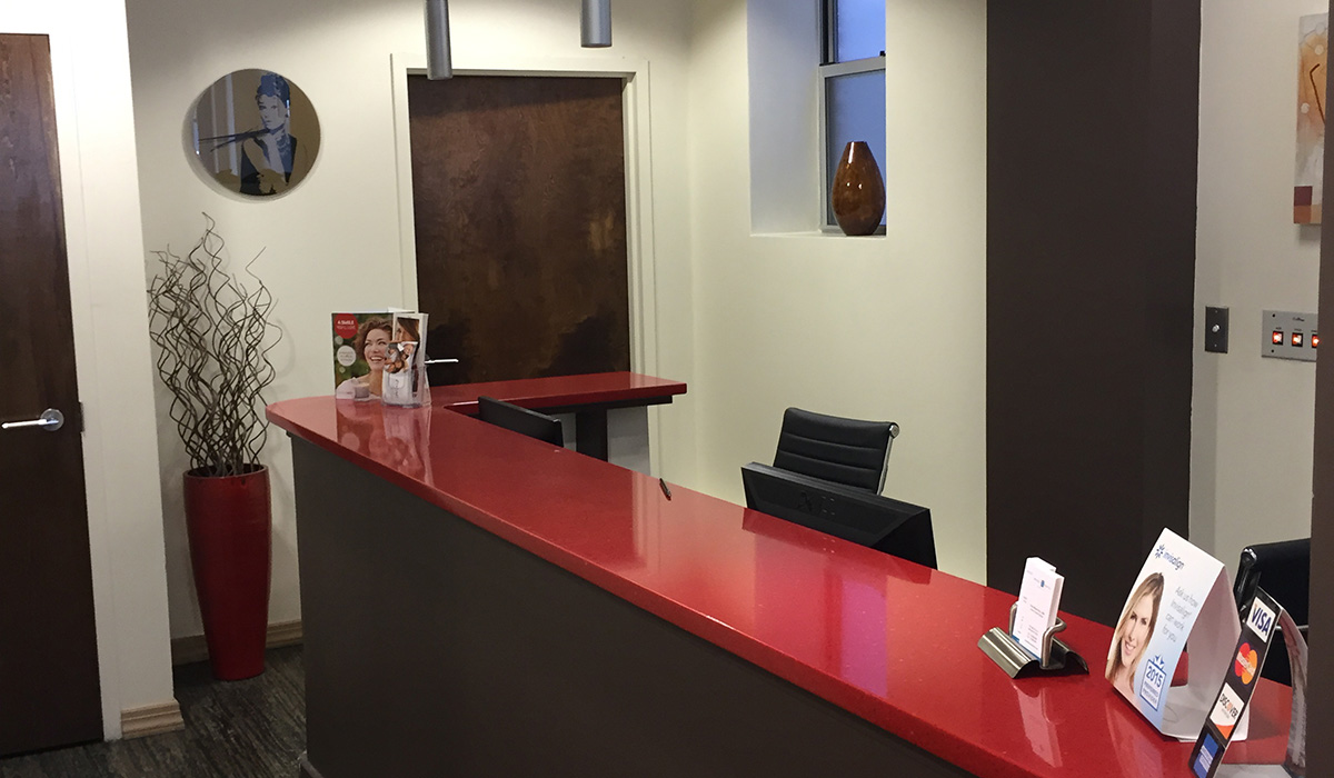 Office reception with a red counter, brown doors in the background